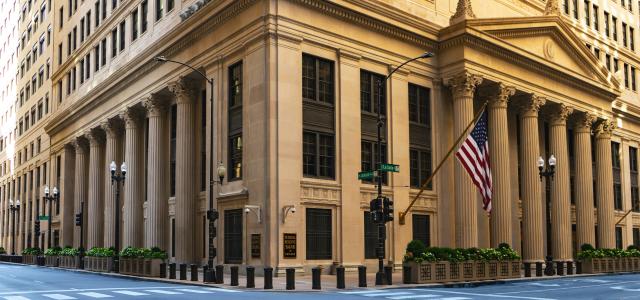 a large building with columns and a flag on the corner by Joshua Woroniecki courtesy of Unsplash.